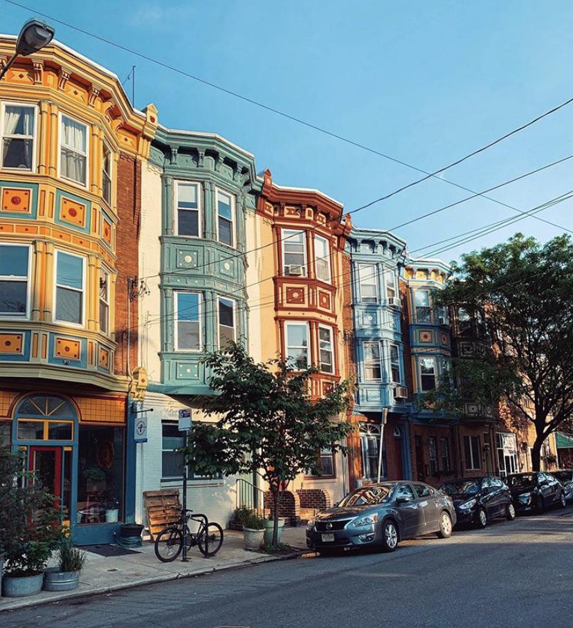 Bella Vista street lined with colorful Victorian-style rowhouses and parked cars.