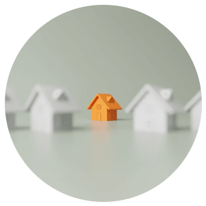 Small orange model house centered between two blurred white houses.