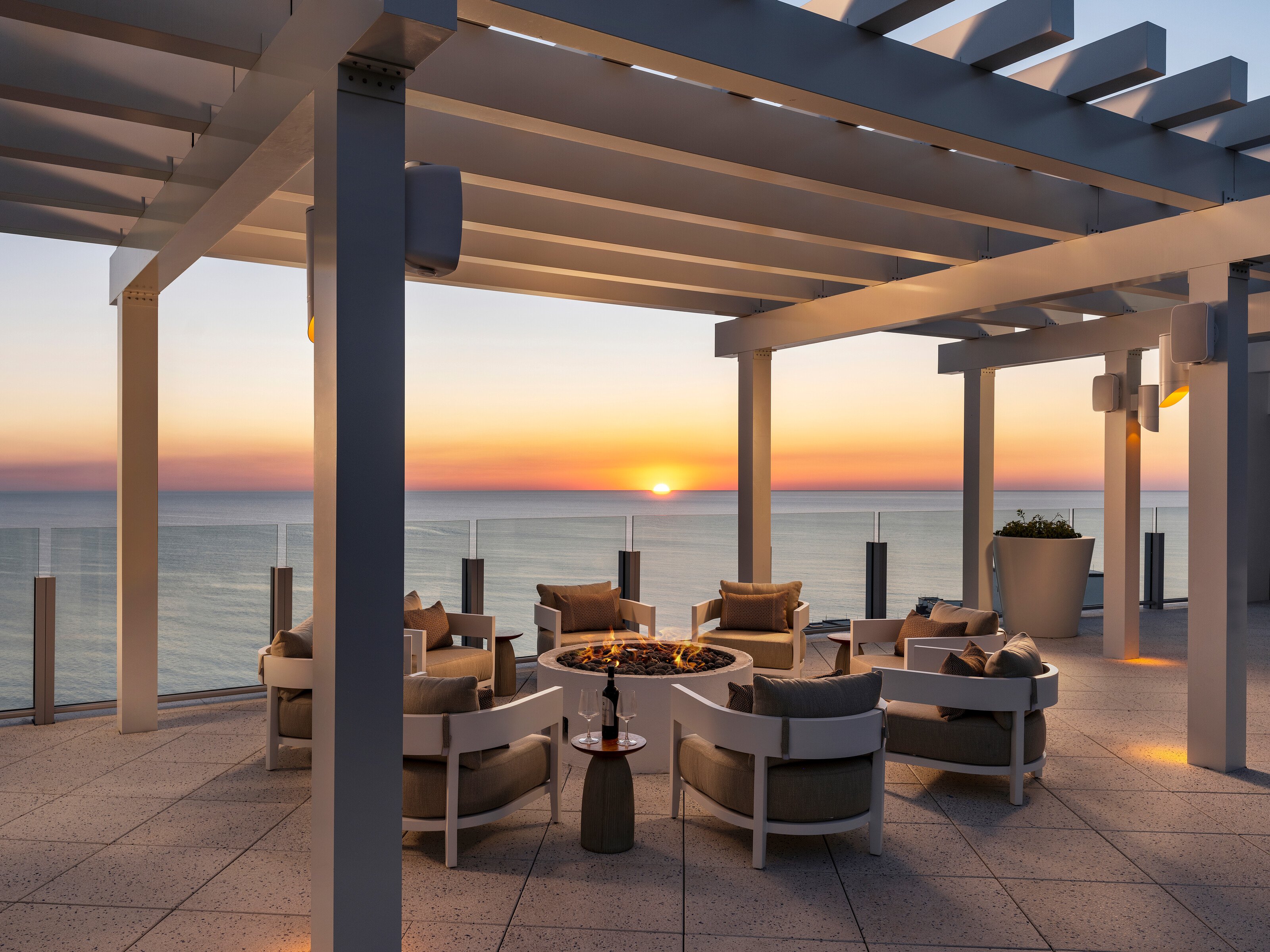 Rooftop lounge with a fire table at sunset over the Gulf at The Ritz-Carlton Residences, Naples