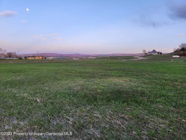 Green field stretching toward Craig and low hills beneath a pastel dusk sky.