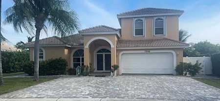 Two-story stucco home with an arched entry, two-car garage, and stone-paver driveway.