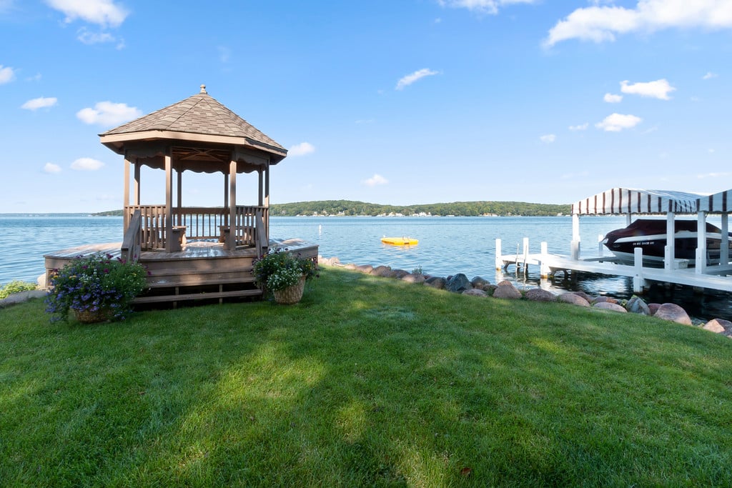 Lakeside lawn with a wooden gazebo and covered dock beside the water.
