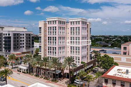 Pink-and-white multi-story building among palm-lined streets and neighboring buildings in East Boca Raton.