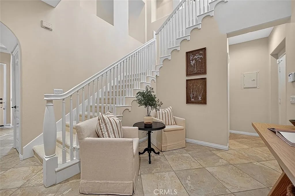 Entry foyer with a sweeping white staircase and a seating nook beneath it.