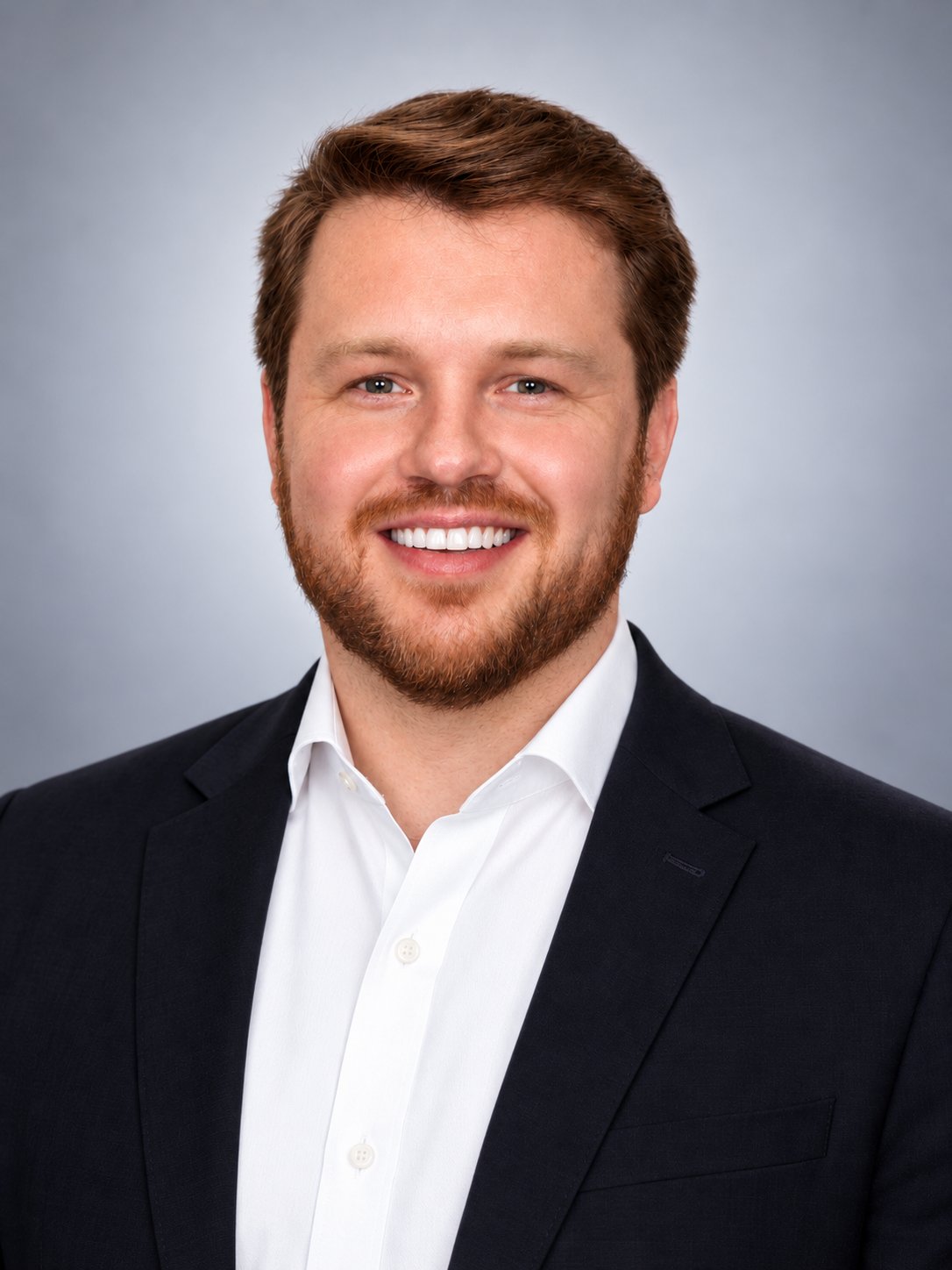 Eoin O’Driscoll smiling in a dark suit jacket and white shirt.
