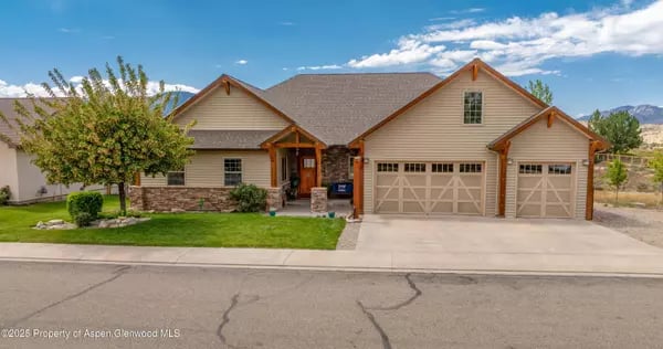 Tan Rifle home with two garage doors, stone accents, and a landscaped front lawn.
