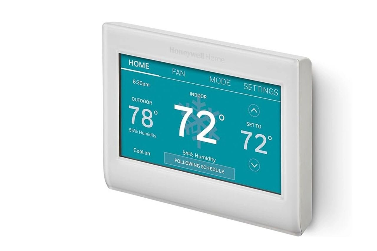 White thermostat with blue display shows indoor/outdoor temperature, humidity, and cooling schedule.