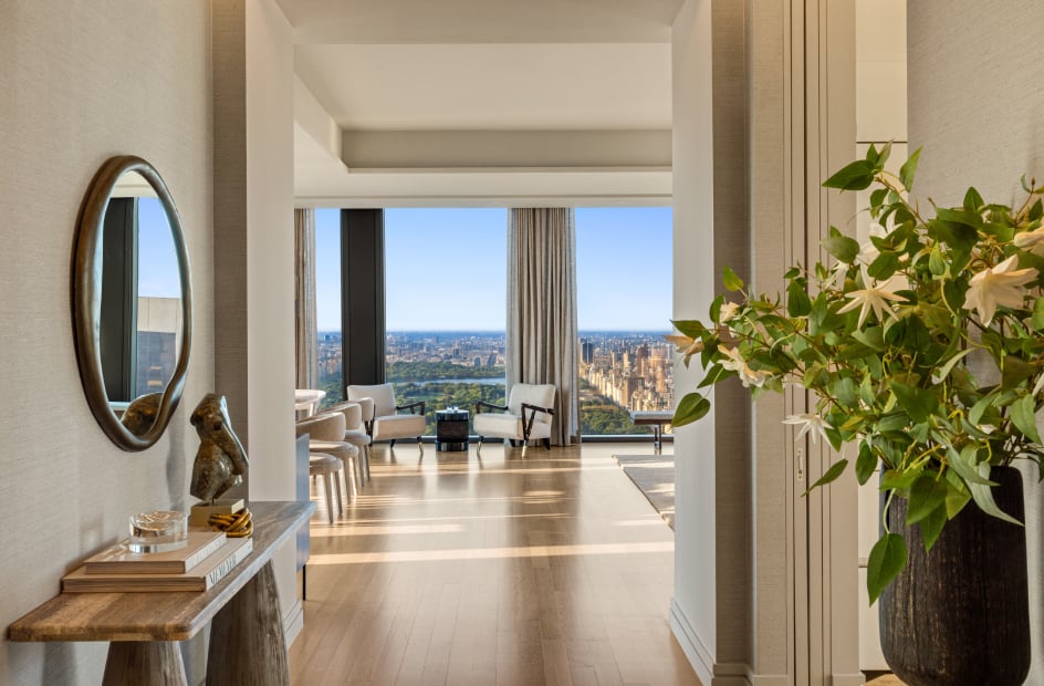 Furnished apartment opens to floor-to-ceiling windows with a sweeping city skyline view.