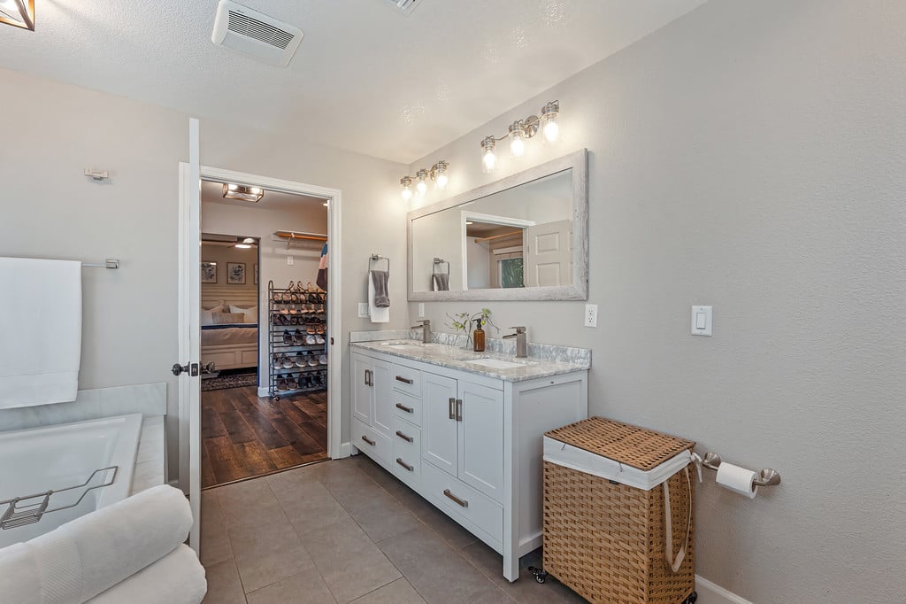 Bathroom with a double-sink vanity and large mirror beside a bathtub.