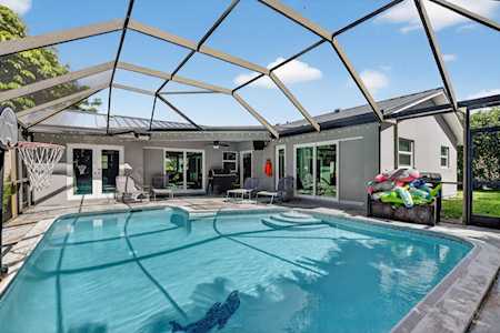 Backyard pool beneath a screened enclosure, with a basketball hoop and colorful floats.