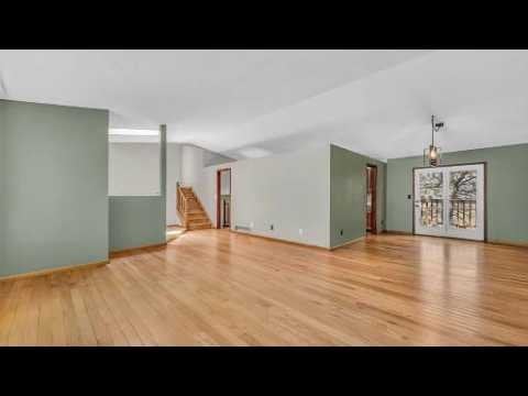 Vacant living area with hardwood floors, a staircase, and glazed double doors.