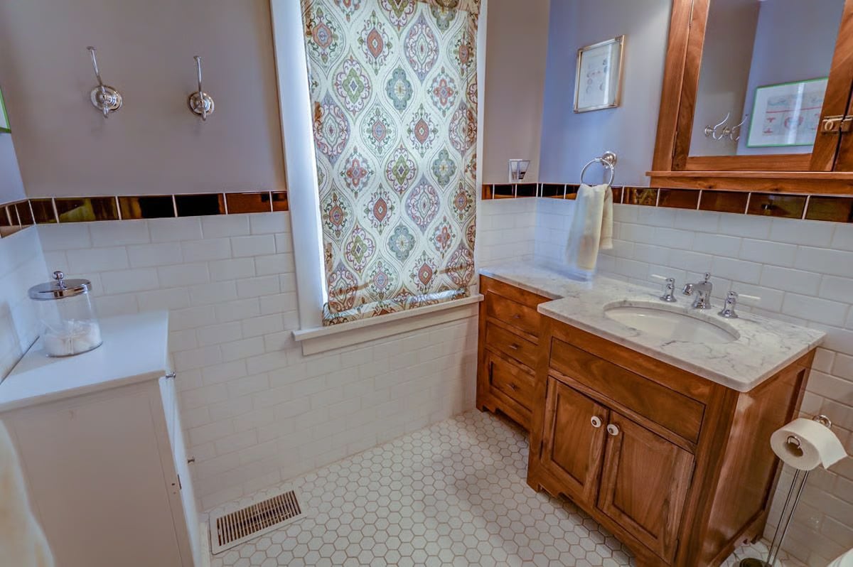 Bathroom with a wood vanity, marble countertop, and patterned shower curtain