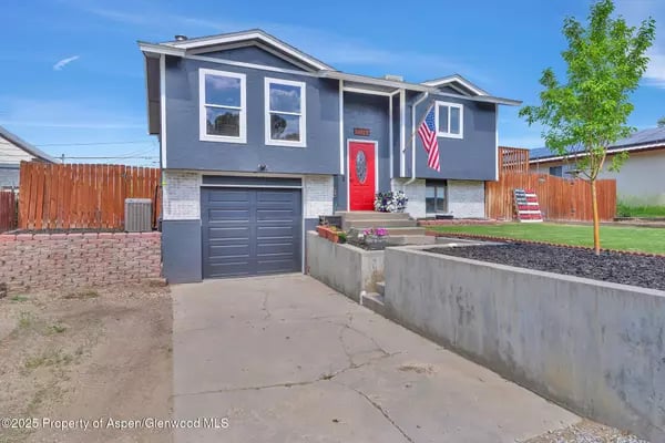Gray two-story house with a red front door, attached garage, and American flags.