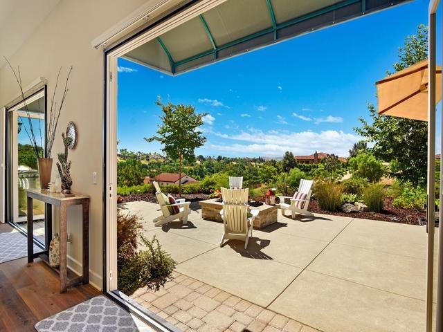 Patio with white Adirondack chairs and landscaped gardens overlooking distant rooftops.