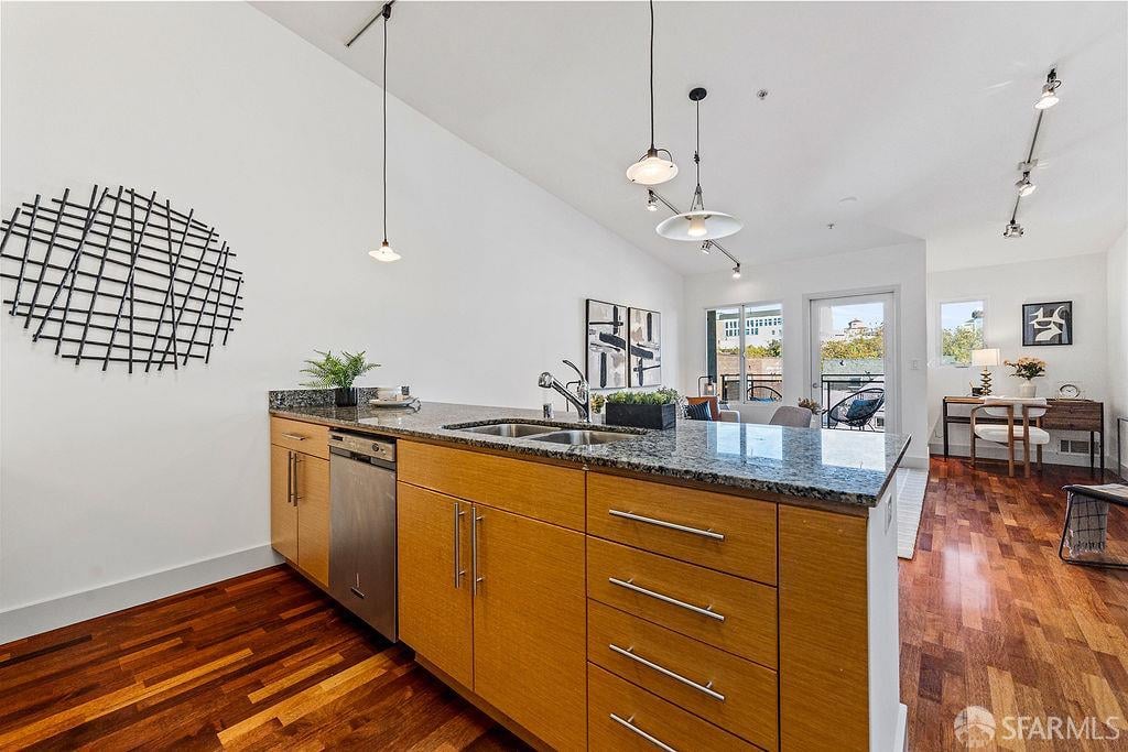Open-plan kitchen with a granite island, warm wood cabinetry, and hardwood floors.