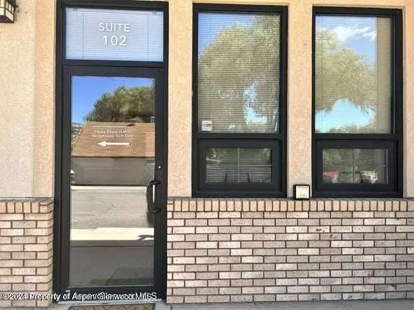Commercial building entrance with a glass door marked Suite 102 and two large windows.