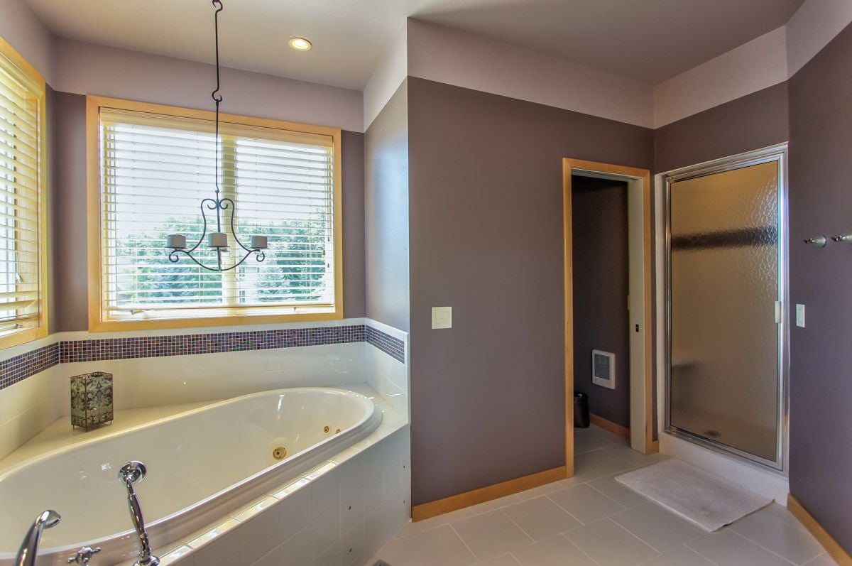 Bathroom with a built-in jetted tub beneath a wide window and a glass-enclosed shower.