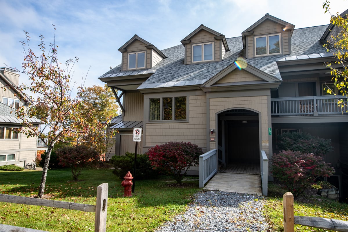 Seasonal rental building with three roof dormers and a covered entrance reached by a wooden ramp.