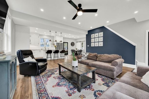 Open-concept living room with a navy accent wall, gray sectional, patterned rug, and kitchen island.