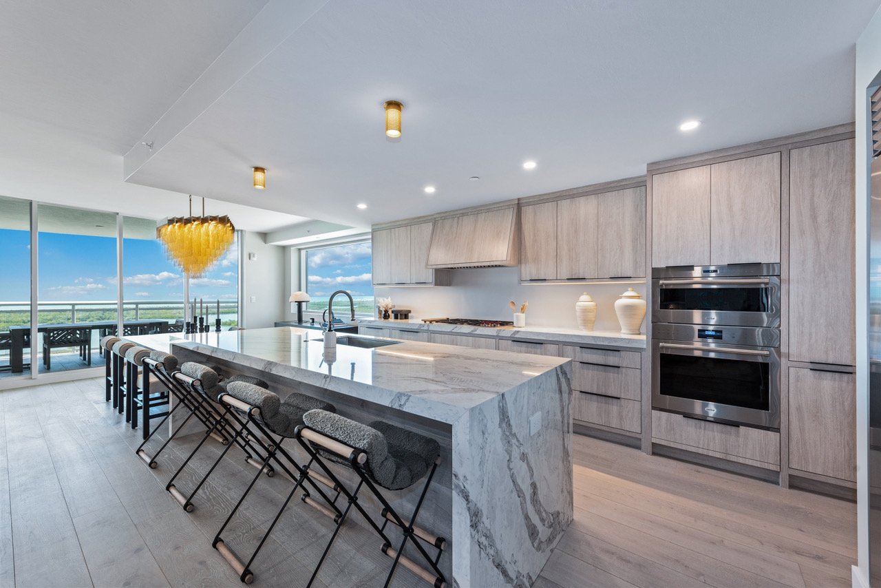 Kitchen with a marble waterfall island and water views in a Kalea Bay residence