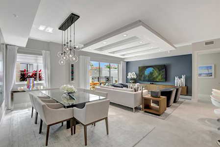 Open-plan living and dining room with a glass table, sectional sofa, and coffered ceiling.