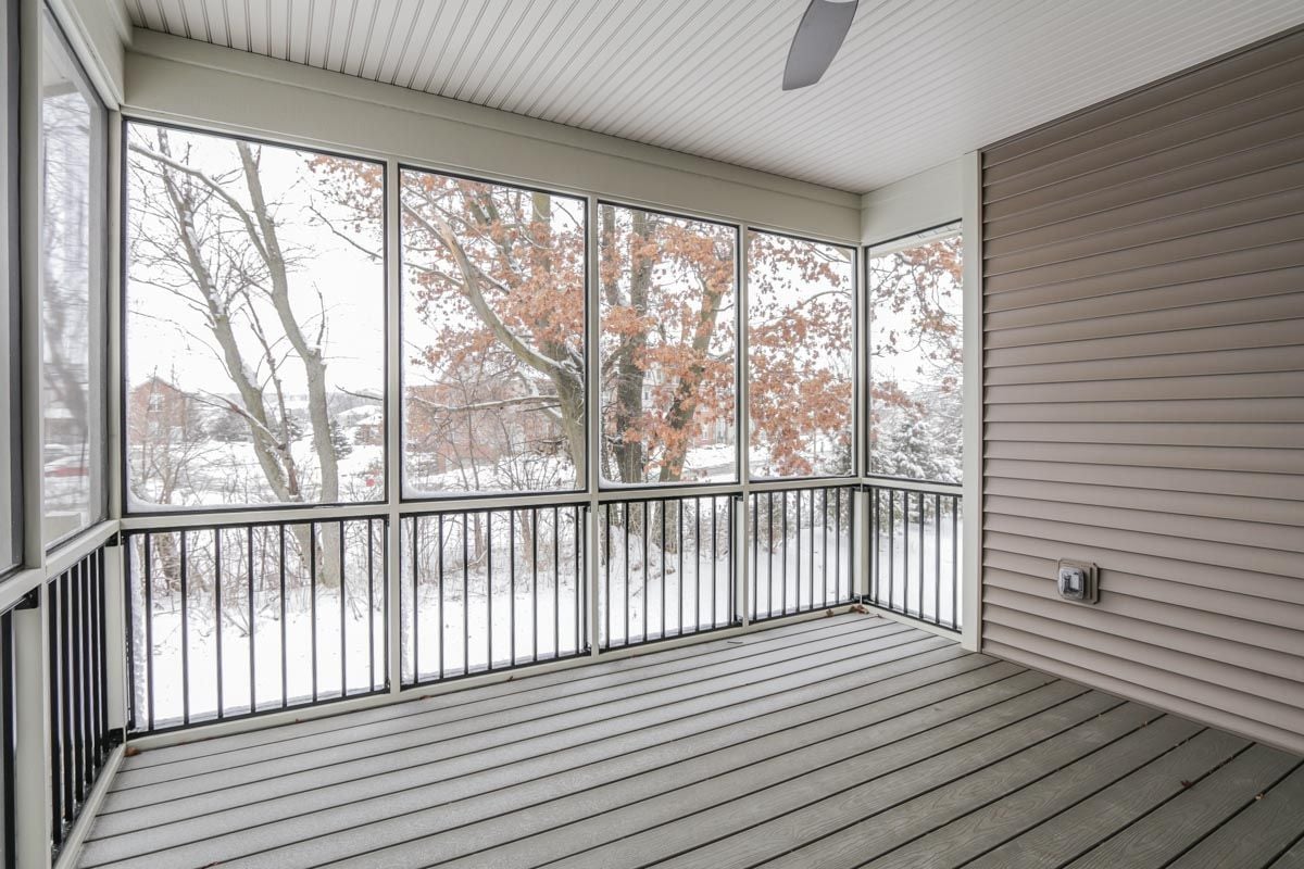 Enclosed porch with wide screened windows overlooking a snow-covered yard.