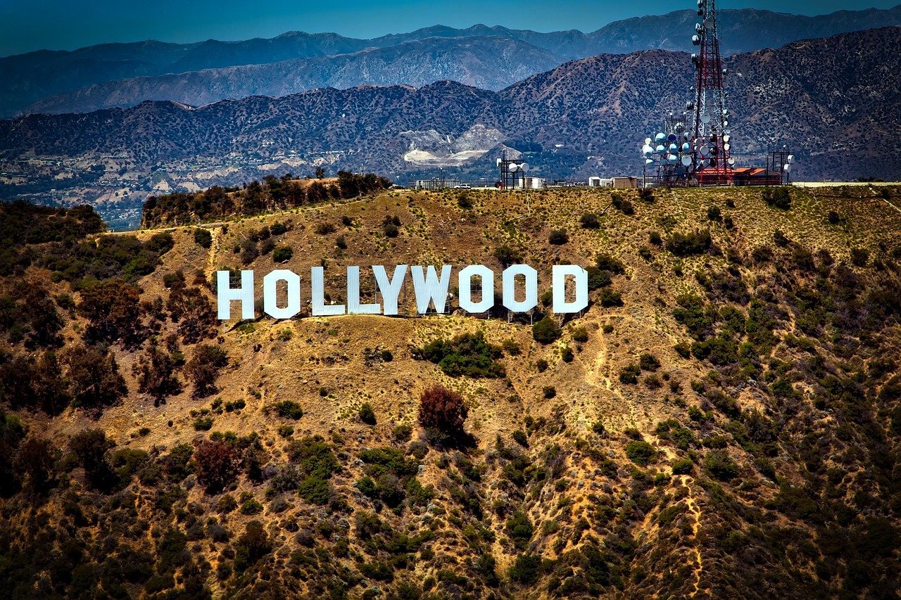The iconic Hollywood Sign on the Santa Monica Mountains in Los Angeles, with the San Gabriel Mountains visible in the distance.