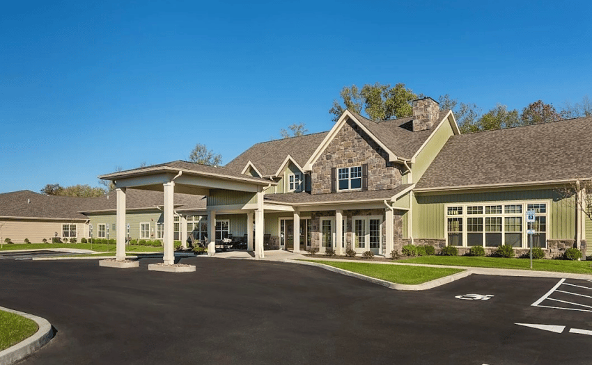 Senior living community exterior with a stone-accented entrance and covered porte-cochere.