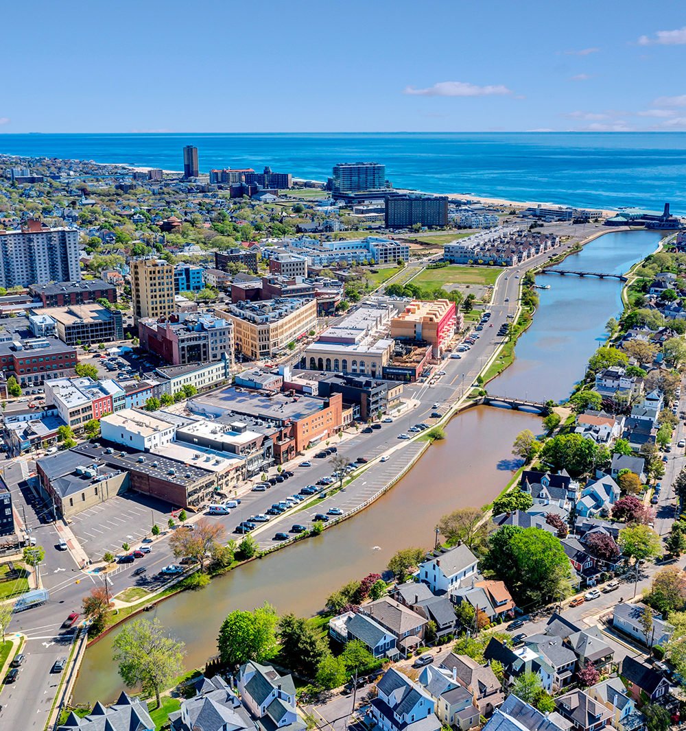 Aerial view of a coastal downtown, river inlet, and oceanfront buildings.