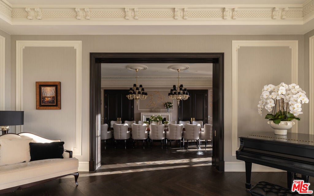 Furnished living and dining room with ornate moldings, dark hardwood floors, and a black grand piano.