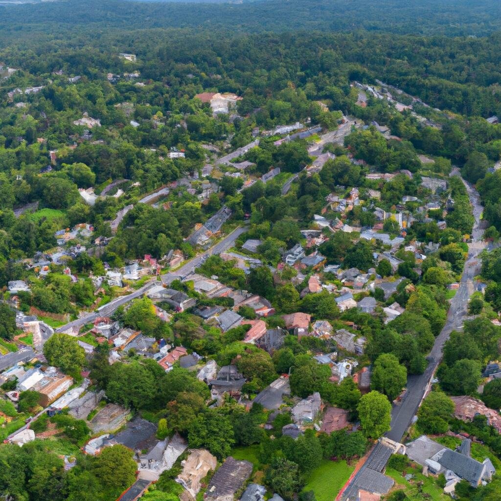 Aerial view of homes among trees, with winding roads and a wooded mountain ridge.