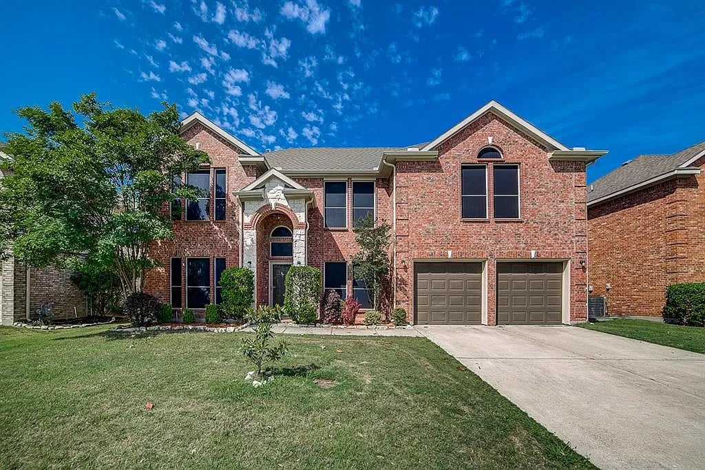 Two-story red-brick home with an arched entry, double garage, and broad front lawn.