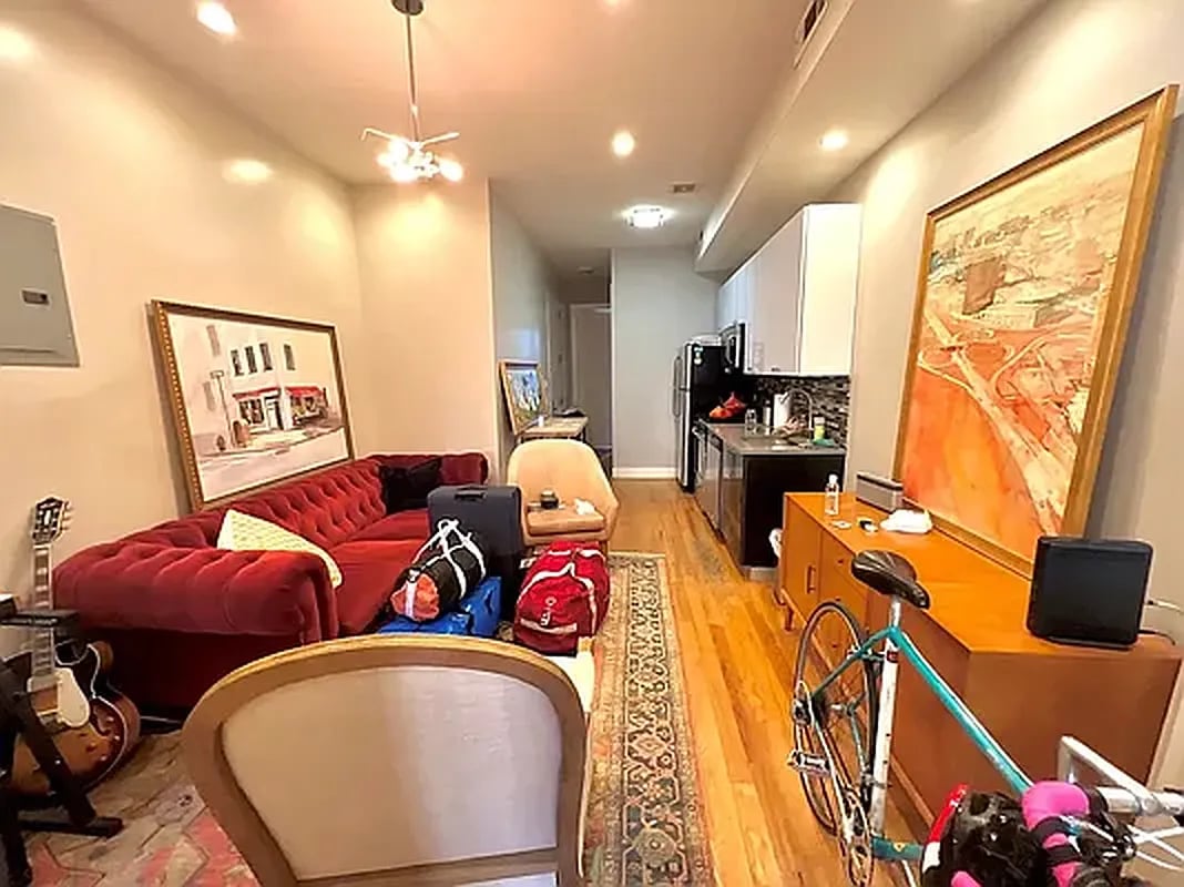 Furnished apartment living room with a red sofa, hardwood floors, and an open kitchen.