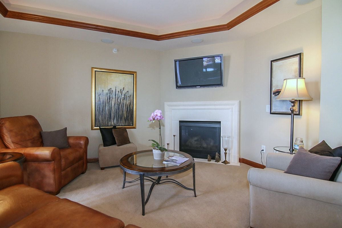Living room with a white fireplace, mounted TV, leather recliners, and gray sofa.