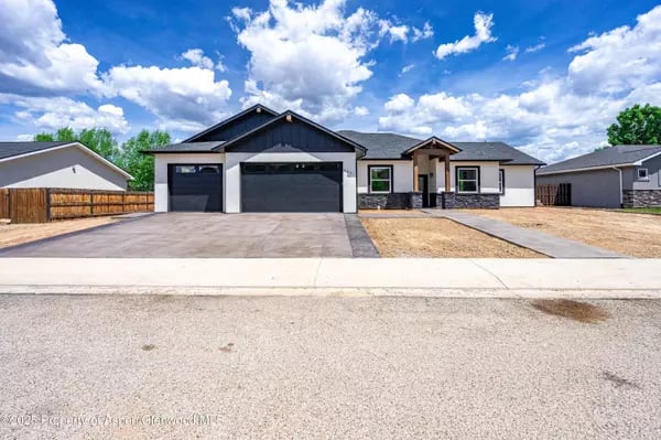 Modern single-story home with a two-car garage, covered entry, and broad driveway.