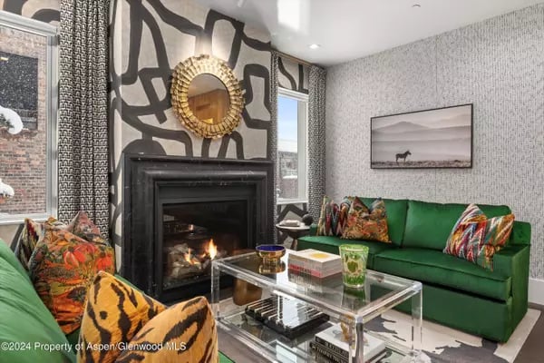Living room with a black fireplace, emerald-green sofa, and patterned feature wall.