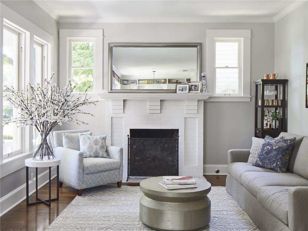 Living room with a painted brick fireplace, oversized mantel mirror, and built-in cabinetry, in a Pemberton Heights home on Northwood Road in Austin, Texas. Architectural renovation by McWalters Collaborative.