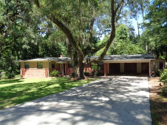 A brick home surrounded by trees and lush grass in the foreground, showcasing a serene outdoor environment.