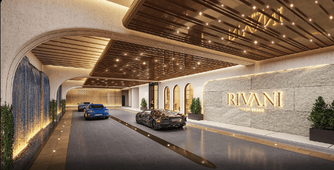 RIVANI building entrance with a covered drive, illuminated stone walls, and parked cars.