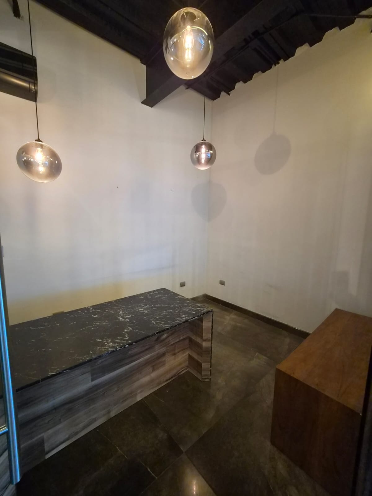 Office reception area with a veined stone counter, wood front, and glass pendant lights.
