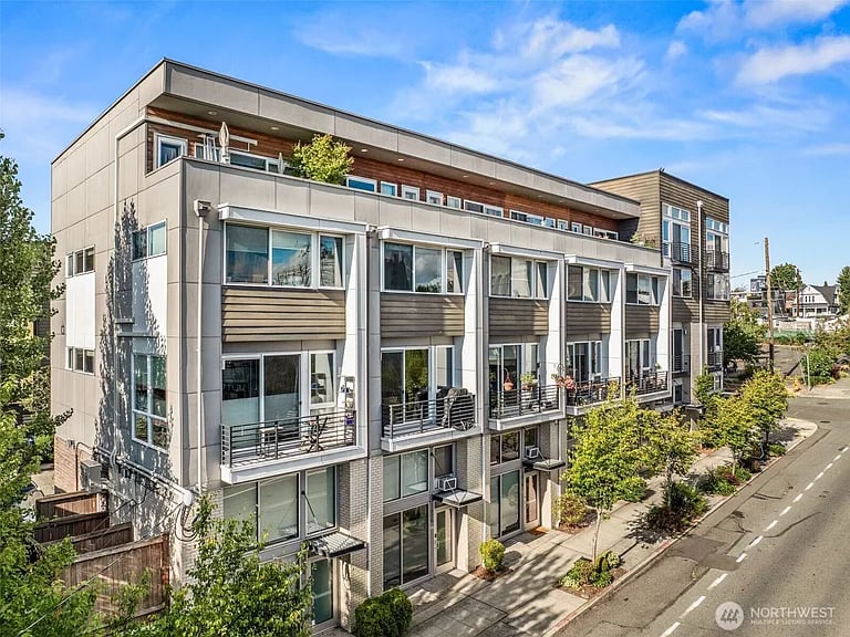 Modern multi-story Seattle residence with private balconies and rooftop terrace along a tree-lined street.