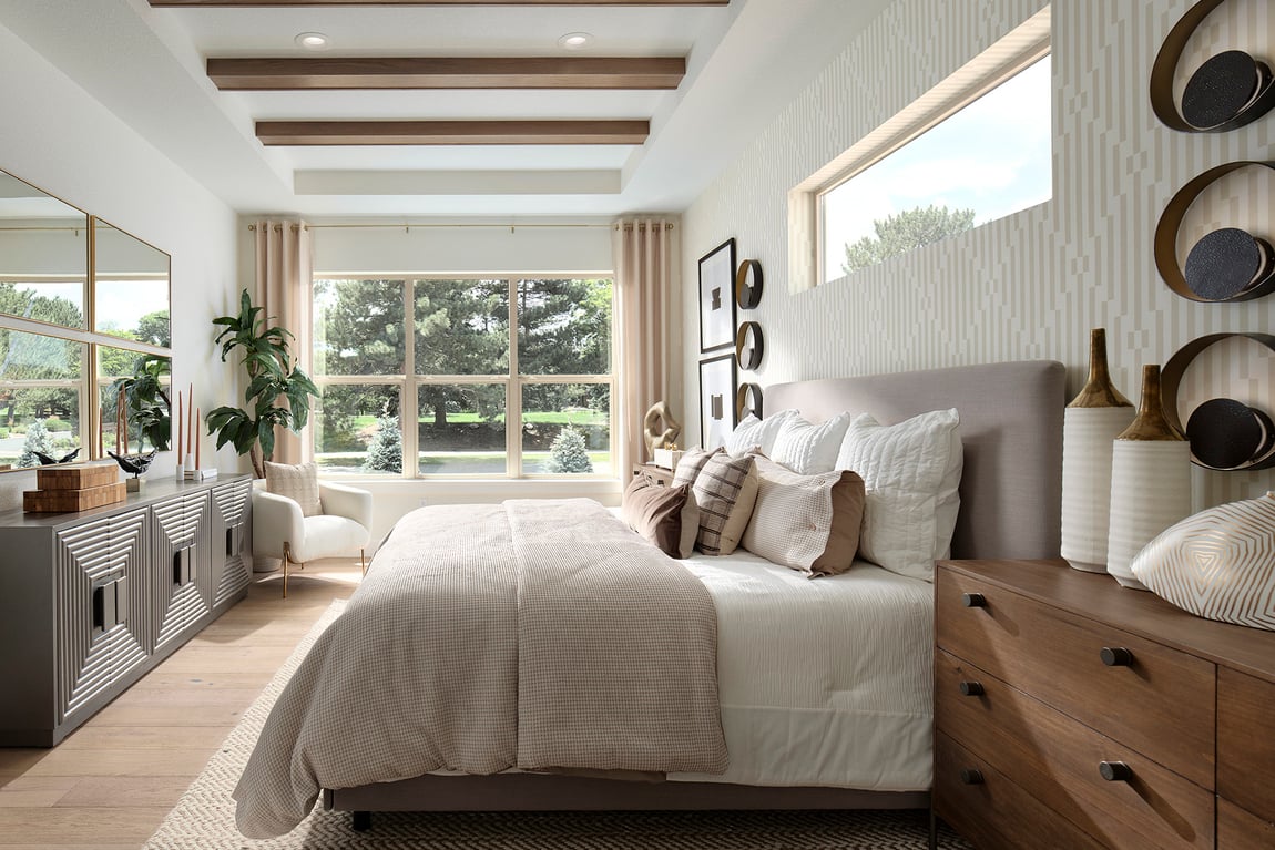 A serene primary bedroom suite with plush bedding and light wood flooring, representing the quiet sanctuary found in Silverwood’s luxury homes.