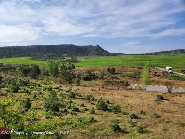 Open fields and scrubland near Silt, with a small pond and wooded hills.