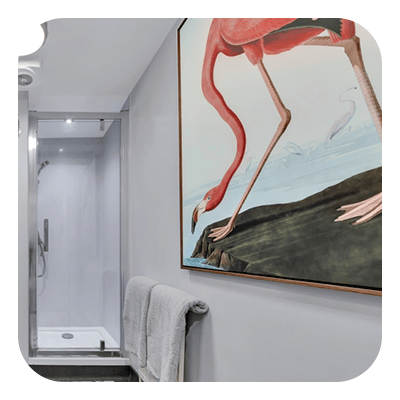 Bathroom with a glass shower and a large framed painting of flamingos.