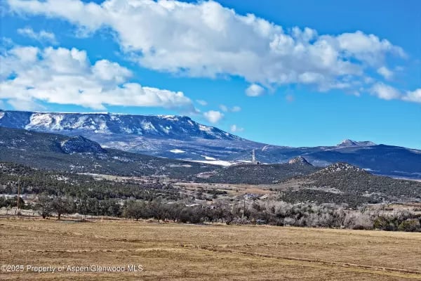 Mountain range beyond a dry open field near Collbran, Colorado.