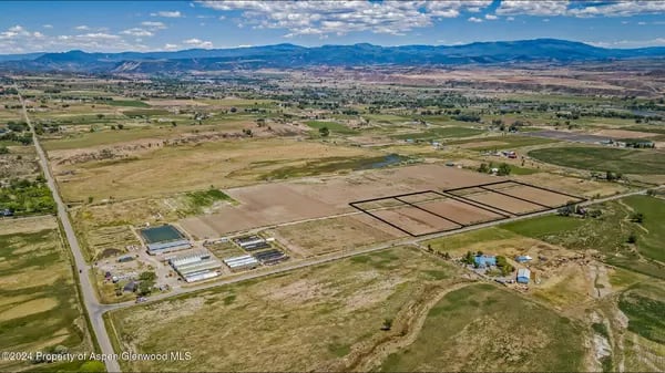 Aerial view of agricultural fields and scattered buildings in a mountain valley.