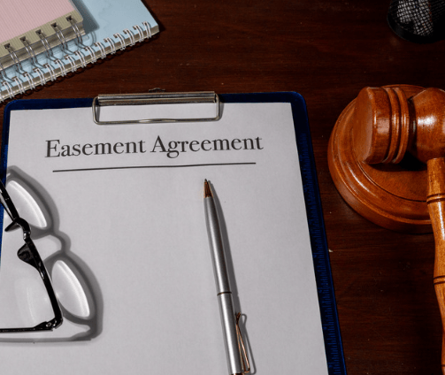 Easement agreement on a clipboard beside a gavel, eyeglasses, and pen.