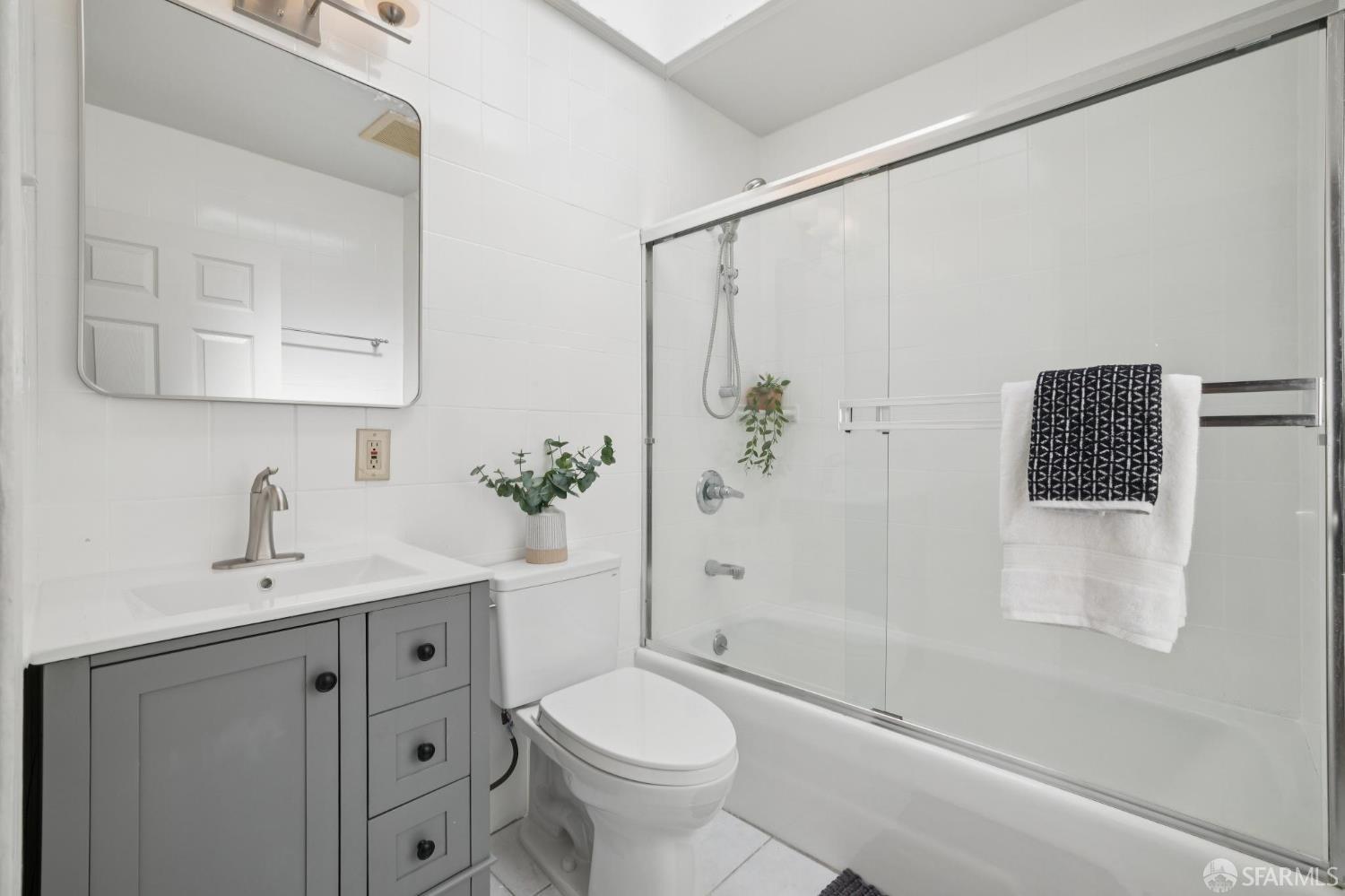 Bathroom with a gray vanity and a glass-enclosed tub and shower.
