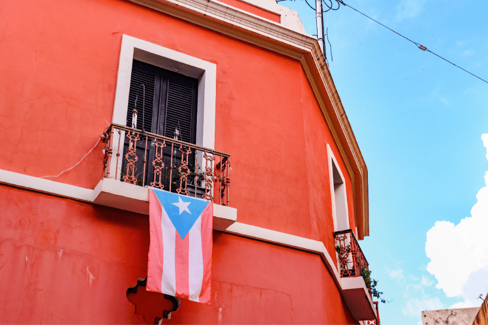 Puerto Rican flag hanging from balcony on vibrant red building