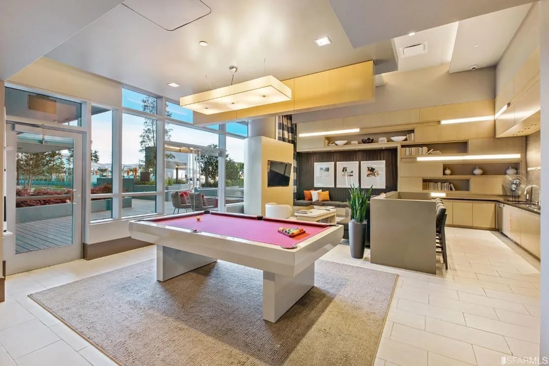 Arden Residences lounge with a red pool table, large windows, and seating.